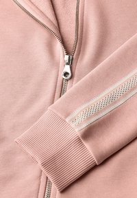 Giacca rosa con zip, caratterizzata da polsini a costine e un tessuto testurizzato. Un dettaglio notevole include un accentuazione a strisce color crema sulla manica.