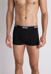 Schwarze Baumwoll-Boxershorts mit einem weißen BOSS-Logo am Bund. Eng anliegendes Design mit glatter Textur und ohne sichtbare Muster.