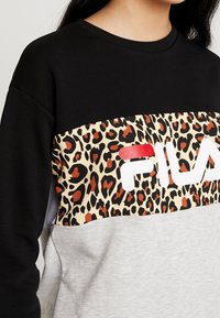 Czarna i szara bluza z szerokim pasem w panterkę z czerwonymi akcentami i białym logo "FILA", wykonana z miękkiego, teksturowanego materiału.