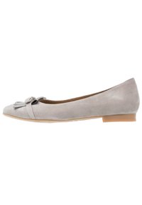 Zapato plano de ante gris claro con tacón bajo y borlas decorativas y lazo en la puntera, vista lateral sobre fondo blanco.