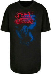 Juodas medvilninis marškinėliai su grafika, vaizduojančia figūrą prieš mėlyną foną, o virš dizaino raudonais rašmenimis parašyta "OZZY OSBOURNE".