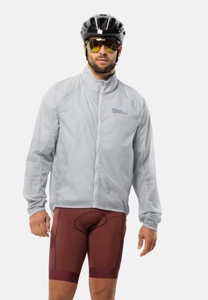 Veste de cyclisme gris clair avec une fermeture éclair à l'avant, des manches longues et un logo. Associée à un short de vélo rouge foncé. Tissu lisse et léger.