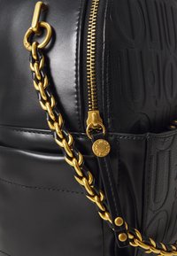 Borsa in pelle nera con motivo stampato, zip e accessori dorati, dotata di tracolla a catena intrecciata e superficie liscia.