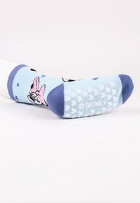 Calze per bambini con una base azzurro chiaro, disegni di personaggi dei cartoni animati neri e rosa, punta rinforzata e fondo con grip non scivoloso testurizzato.