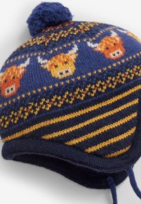 Cappello di lana color navy con disegni a motivi di mucche Highland arancioni e gialli sulla corona, dotato di pom-pom e orecchie a punta con strisce.