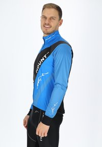 Langdurige fietsjack met lange mouwen in blauw en zwart, voorzien van een ritssluiting aan de voorkant, mesh textuur en een logo op de borst. De aansluitende pasvorm verbetert de mobiliteit.