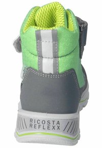 Zapatilla alta gris con parte superior de malla verde, acentos blancos y una correa de Velcro. Presenta un patrón texturizado y una marca en el talón.