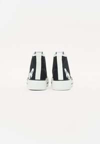 Høye sneakers laget av svart kanvas med hvite detaljer. Har en teksturert såle og et grafisk detalj på sidene.
