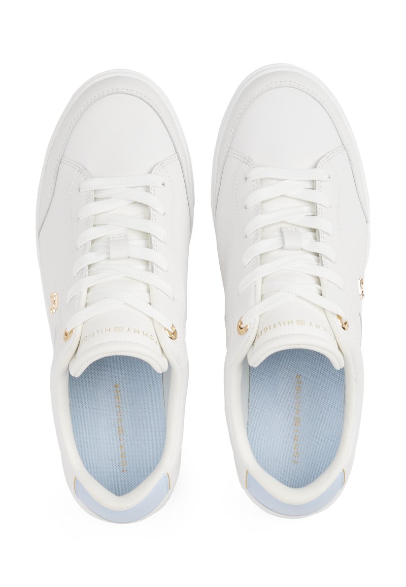 Białe sneakersy o gładkiej powierzchni, okrągłym nosku, płaskich białych sznurowadłach i złotych akcentach. Jasnoniebieskie wkładki kontrastują z białym wnętrzem.