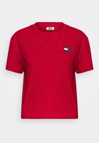 Czerwona, krótkosleeve, skrojona koszulka z okrągłym dekoltem i małą naszywką z logo Tommy Jeans na lewym górnym klatce piersiowej.