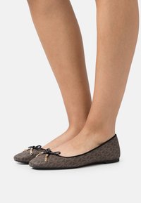 Flache Ballettschuhe aus braunem gemustertem Stoff verfügen über eine schwarze Schleife mit goldenen Hardware-Akzenten. Die Schuhe haben eine runde Zehenform und ein schlankes Profil.