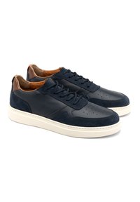 Granatowe skórzane i zamszowe sneakersy z perforowanymi detalami, kontrastującym brązowym akcentem na pięcie i lekką białą gumową podeszwą.