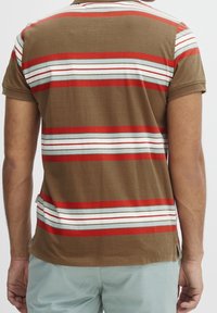 Chemise marron à manches courtes avec des rayures horizontales rouges, blanches et bleues. Tissu doux, col rond et fentes latérales à l'ourlet.