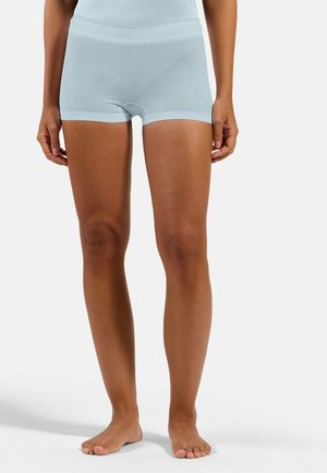 Woman wearing light blue seamless high-waist boyshorts and matching top, standing barefoot against a plain background.