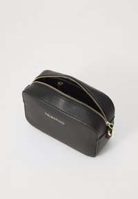 Borsa cosmetica nera in pelle con finitura testurizzata, forma arrotondata, doppia zip dorata e logo impresso sul davanti.