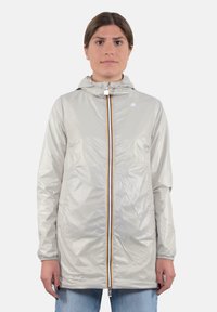 Giacca da pioggia leggera e argento con cappuccio, zip frontale con una striscia colorata, polsini elastici e due tasche laterali.