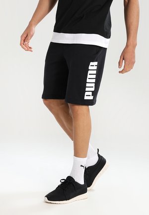 Czarne sportowe szorty wykonane z mieszanki bawełny z białym logo "PUMA" po lewej stronie. Zestawione z czarnymi trampkami i białymi skarpetkami.