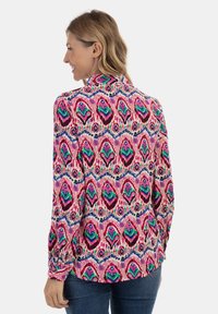 Camicia a maniche lunghe con un vivo motivo astratto nei colori rosa, verde e blu, dotata di colletto e polsini con bottoni. Realizzata in tessuto leggero.