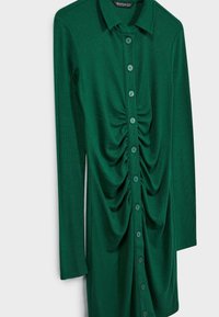 Robe à manches longues vert foncé côtelée avec col, fermeture à boutons sur le devant et détails froncés le long de la ligne de boutons.