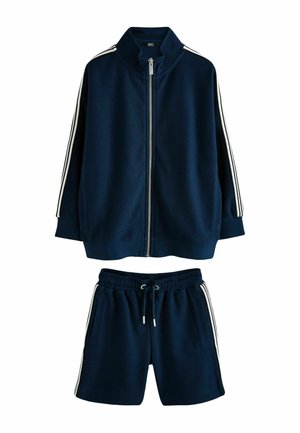 Marineblaues Sportset mit Reißverschlussjacke und Shorts, ausgestattet mit weißen Seitenstreifen, strukturiertem Stoff und elastischem Bund.