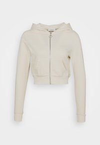 Felpa cropped di colore crema con maniche lunghe, zip frontale con tirante a anello e tasca tipo kangaroo.