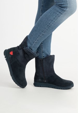 Dunkelblaue Wildleder-Stiefeletten mit Umschlag-Design, seitlichem Reißverschluss und rotem Herz-Akzent. Gummisohle für Halt und Langlebigkeit.