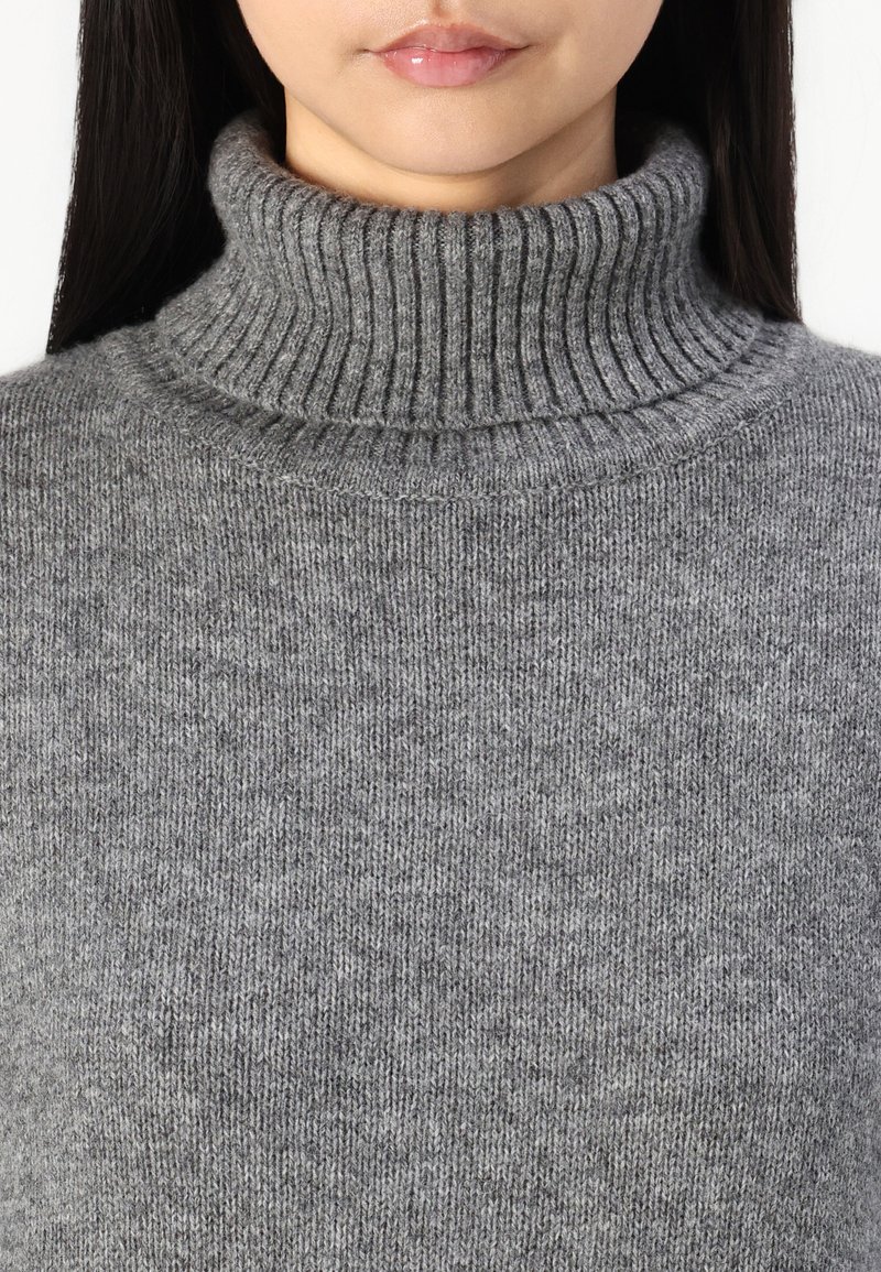 Grau melierter Rollkragenpullover aus weichem, geripptem Strickstoff; verfügt über einen hohen, umgeschlagenen Kragen und eine glatte Textur.