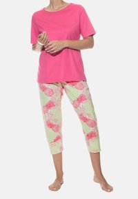 Lyserød kortærmet skjorte parret med cropped bukser med lysegrøn baggrund og tryk af lyserøde ananaser og løv.