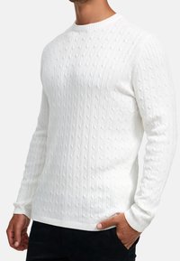 Weißer Strickpullover mit Zopfmuster, langen Ärmeln, rundem Ausschnitt, strukturiertem Muster sowie gerippten Bündchen und Saum. Geeignet für den Freizeitgebrauch.