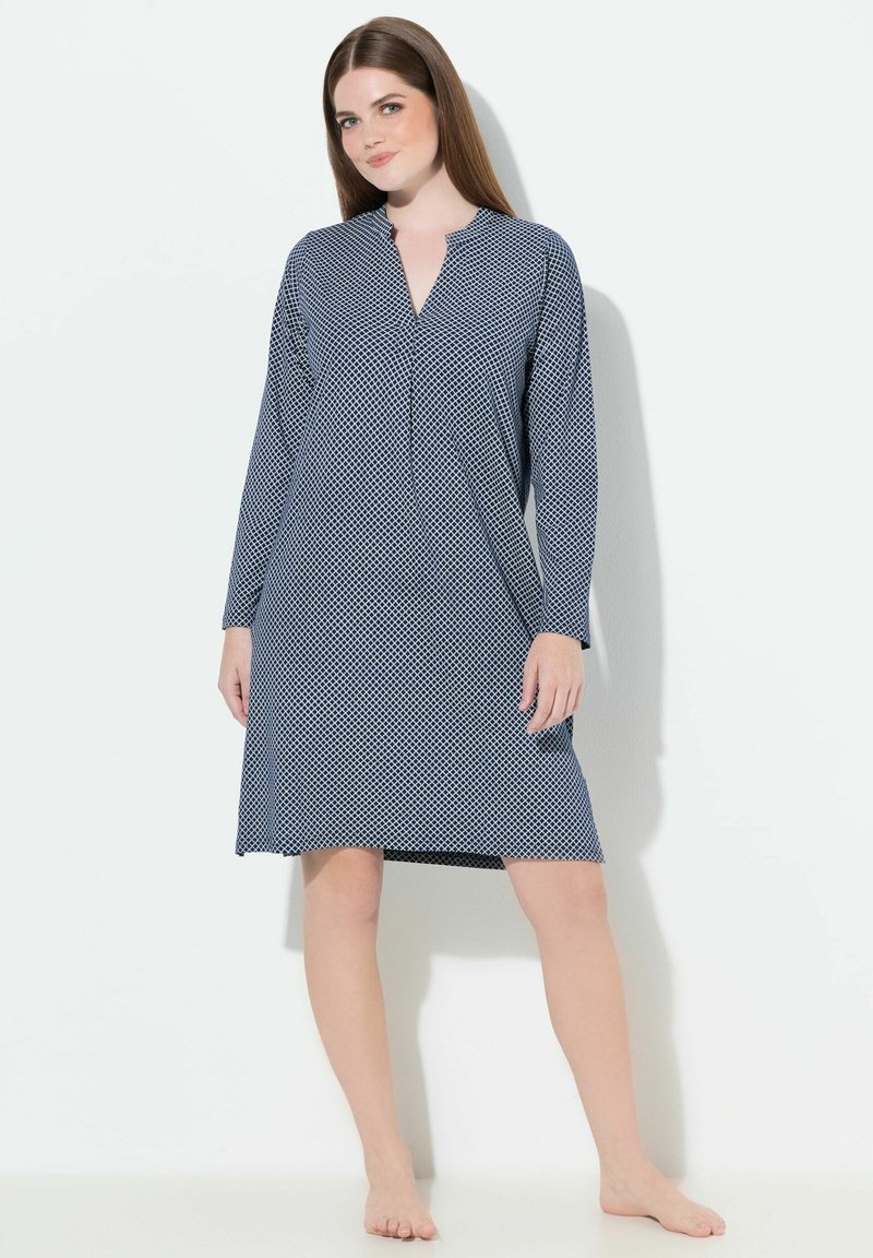 Vestido de manga larga azul marino con patrón geométrico blanco, cuello con muesca, corte relajado y dobladillo a la altura de la rodilla. Textura de tela suave.