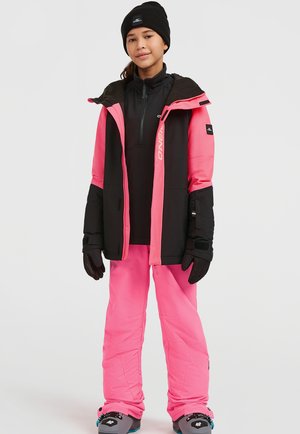 Chaqueta de esquí insulated en rosa y negro con cierre de cremallera y capucha, combinada con pantalones de nieve rosas y guantes negros. Botas de nieve visibles en la parte inferior.
