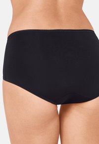 Culotte noire sans couture taille haute avec une texture lisse, ornée d'une fine bordure le long de la ceinture et d'une couture arrière incurvée pour plus de confort.