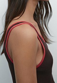 Bruin geribbelde tanktop met contrasterende rode bies op de bandjes, met een brede halslijn en open armsgaten voor een relaxed pasvorm.