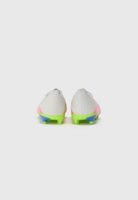 Botas de fútbol con parte superior blanca, detalles en rosa y suela verde. Presentan un perfil bajo y seis tacos para un mejor agarre.