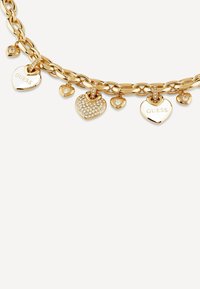 Bracelet en chaîne dorée ornée de plusieurs pendentifs en forme de cœur, certains décorés de strass transparents, avec "GUESS" gravé sur certains cœurs.