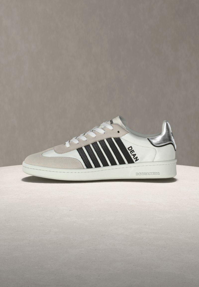Baskets blanches et beige avec des bandes noires, talon argenté, lacets blancs, texte "DEAN" sur le côté, et "DSQUARED2" embossé sur la semelle.