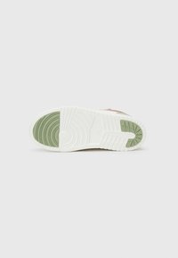 Witte sneakerzool met groene accenten, voorzien van gegroefde patronen voor grip en een circulair designelement bij de hak.