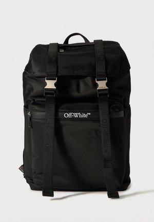 Μαύρο σακίδιο Off-White με δύο μπροστινούς ιμάντες και μεταλλικά αγκράφια, μπροστινή τσέπη με φερμουάρ και χειρολαβή στο πάνω μέρος πάνω σε λευκό φόντο.