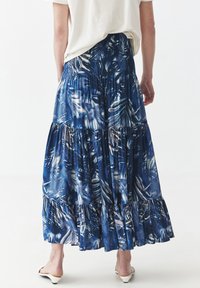 Fustă albastră în trei straturi, cu un model de frunze tropicale, dintr-un material ușor, cu o talie elastică și margine volănată.