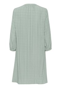 Hellgrünes knielanges Kleid aus weichem, strukturiertem Stoff mit dezenten vertikalen Streifen und gerafften 3/4-Ärmeln. Rundhalsausschnitt.