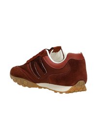 Zamszowe i syntetyczne sneakersy, głównie w kolorze brązowym z białymi akcentami, z grubą gumową podeszwą o teksturowanym wzorze i detalem logo po boku.