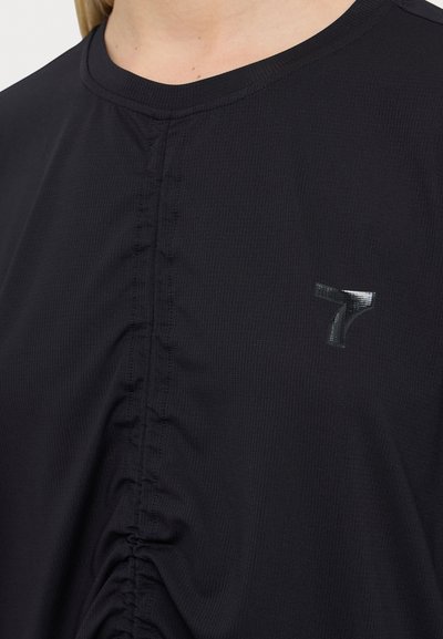 Musta sportlik särk, millel on peened kogumise detailid ja peegeldav logo. Sile tekstuur ja ümmargune kaelus.