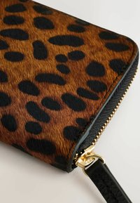 Portafoglio con stampa leopardata, realizzato in un design in pelliccia sintetica testurizzata nei toni del marrone e del nero. Presenta una zip dorata e una tracolla nera.