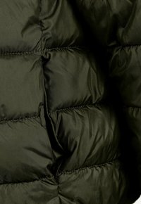 Veste rembourrée vert olive avec un design matelassé, en nylon brillant, et coutures surélevées. Texture douce avec une apparence légère.