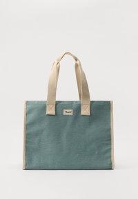 Canvas tote bag i en teal-farge med beige håndtak, som har et lite logomerke og firkantet form. Teksturert stoff, forsterkede sømmer.