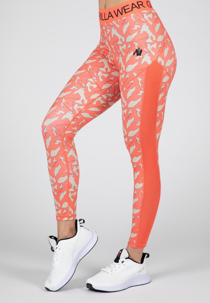 Koraal leggings met een crème abstract patroon, voorzien van een effen oranje zijkant en een zwart logo op de tailleband. Combineert goed met witte schoenen.