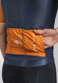 Short-sleeve cycling jersey features a navy upper and orange pocket with elastic trim. It has a slim fit and contrasting stitching details.