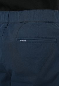 Βαμβακερό παντελόνι σε ναυτικό μπλε με απαλή υφή, διαθέτει πίσω τσέπη και μικρό λογότυπο Barbour. Μινιμαλιστικός σχεδιασμός και ραμμένη εφαρμογή.
