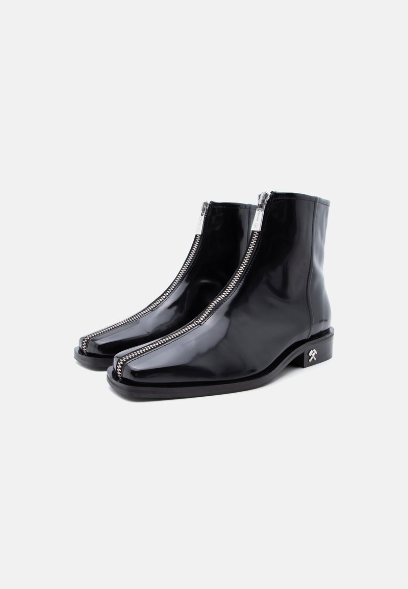 Pair of black glossy ankle boots with front silver zippers and small silver tool logo on the heel, set against a plain white background.