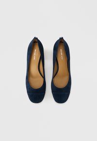 Zapatos planos de ante azul marino con punta en forma de punta redondeada, textura suave, diseño minimalista y una pequeña abertura en el talón.